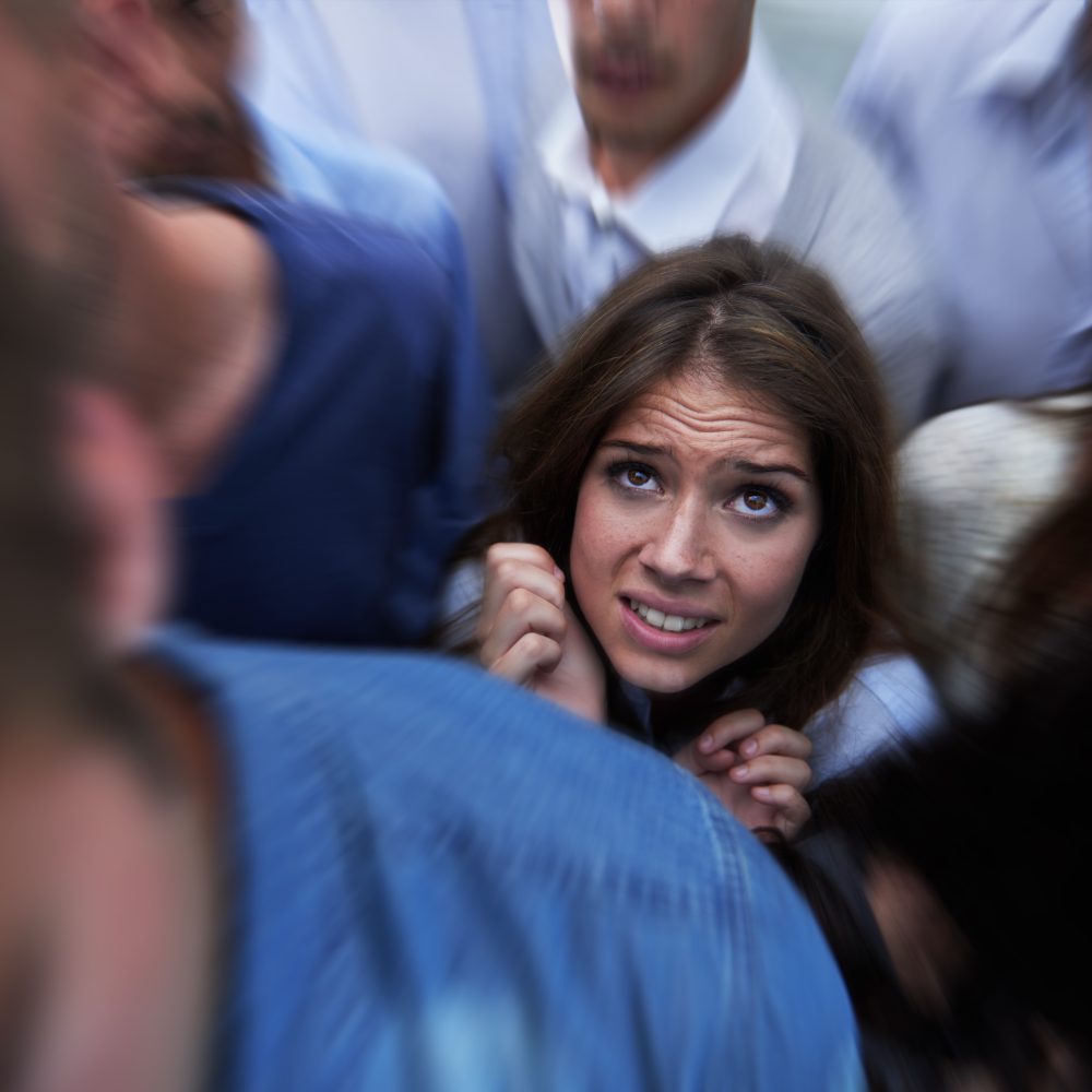 Drowning in people. Shot of a fearful young woman feeling trapped by the crowd
